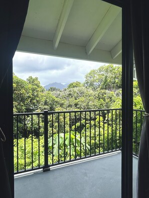 A balcony with a view of lush greenery and mountains in the distance.