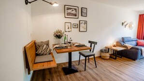 A modern living room with a wooden dining table, a sofa, and a small side table with a lamp.