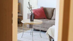 A cozy living room with a sofa, a small round table, and a vase with dried flowers. - Vacation apartment Untersberg 2 persons, 52 sqm (Schönau am Königssee)