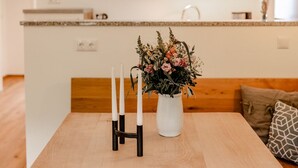 A modern kitchen with a wooden island, white walls, and a flat-screen TV mounted above the counter. - Vacation apartment Untersberg 2 persons, 52 sqm (Schönau am Königssee)