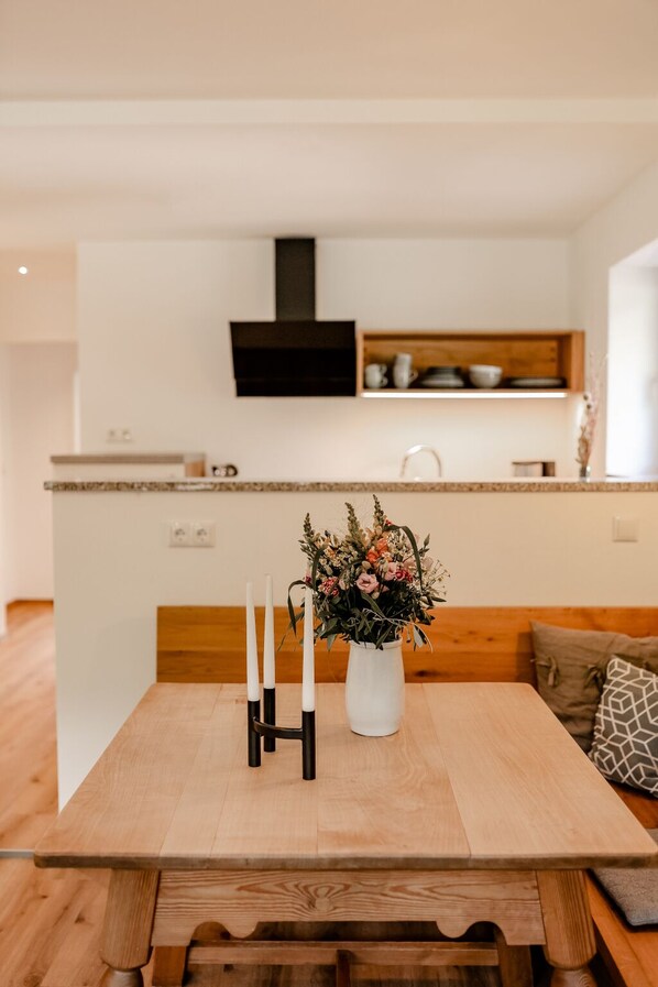 A modern kitchen with a wooden island, white walls, and a flat-screen TV mounted above the counter.