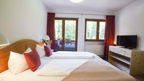 A hotel room with two beds, a TV, a wooden dresser, and a window with curtains. - Vacation apartment Kehlstein 2 persons, 40 sqm (Schönau am Königssee)