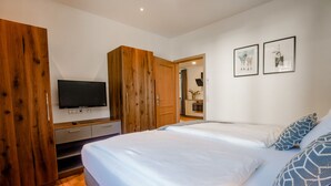Un dormitorio con una cama grande, un armario de madera, un televisor de pantalla plana y dos cuadros en la pared.