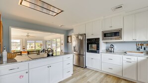 A modern kitchen with white cabinets, stainless steel appliances, and a large island.