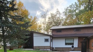 Un quartier résidentiel avec une pelouse bien entretenue, un petit bâtiment doté d’une fenêtre et un arbre.