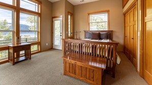 A spacious room with large windows, a ceiling fan, and wooden furniture.