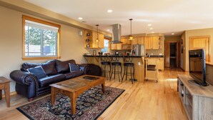 A modern kitchen with wooden cabinets, a stainless steel refrigerator, and a bar area with stools.