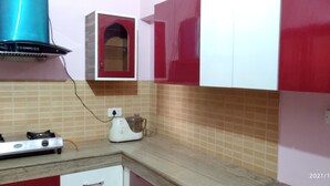 Eine Küche mit einem Gaskochfeld, einem Mixer und einem roten und weißen Schrank.