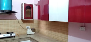 Une cuisine équipée d’une cuisinière à gaz, d’un mixeur et d’un meuble rouge et blanc.