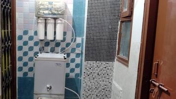 Casa de banho com sistema de filtragem de água, parede revestida com padrão azul e branco, e porta de metal.