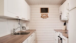 Cocina compacta con armarios blancos, encimeras de madera, cafetera y un cartel que indica disponibilidad de WiFi.