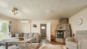 Una sala de estar acogedora con una chimenea de piedra, un sofá, un sillón y una alfombra.