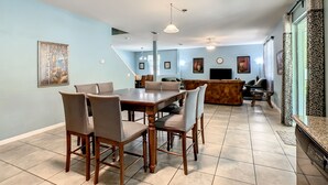 A spacious living area with a dining table, chairs, a sofa, and a television. - 8br/5ba Pool Villa,Near Disney, Seaworld, Convention Ctr (Kissimmee)