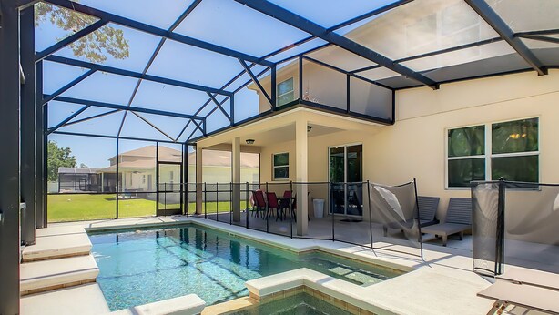 A swimming pool with a glass enclosure, outdoor seating, and a view of the surrounding area. - 8br/5ba Pool Villa,Near Disney, Seaworld, Convention Ctr (Kissimmee)