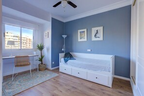 Une chambre à coucher comprenant un lit, un bureau, une chaise, une fenêtre et un ventilateur de plafond.