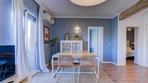 Un coin repas comprenant une table et des chaises, un luminaire suspendu, un meuble blanc avec des portes en verre et une plante.