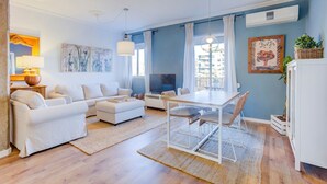 Un salon moderne comprenant un ensemble de canapés, une table à manger avec des chaises, un téléviseur et des œuvres d’art accrochées aux murs.