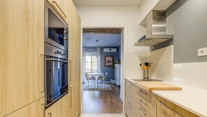 Une cuisine moderne avec des meubles en bois, des appareils électroménagers en acier inoxydable et une vue sur la salle à manger.
