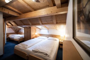 Ein Zimmer mit zwei Betten, Holzbalkendecke und einem Fenster.