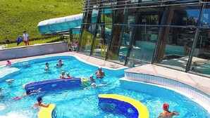 Una piscina con cerramiento de vidrio, rodeada de césped.