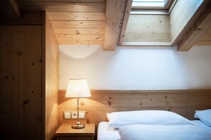 A room with wooden walls, a bed with white bedding, a nightstand with a lamp, and a skylight. - "Villa Stella Appartamento Stella Dream" near the ski lifts with mountain view (Ortisei)