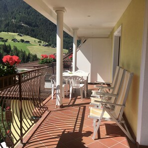 Ein Balkon mit Tisch und Stühlen, einem Geländer und Blick auf eine grüne Landschaft.