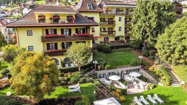 Un hotel de varios pisos con balcones, un jardín y zonas de estar al aire libre.