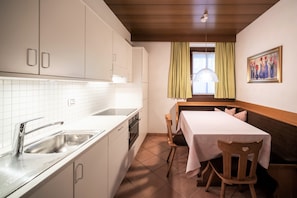A kitchen with white cabinets, a sink, and a dining area with a table and chairs.