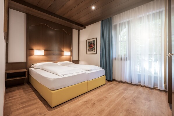 Una cama doble con cabecera de madera, una mesita de noche y una lámpara de pared.