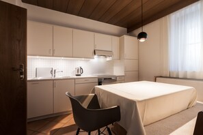 A modern kitchen with white cabinets, a dining table, and a black chair.
