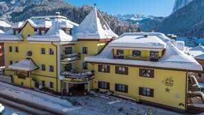 A yellow building with a balcony, a sign reading 'Stella Residence,' and snow-covered surroundings.