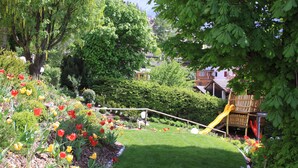 A garden with a slide, a lawn, and a variety of flowers.