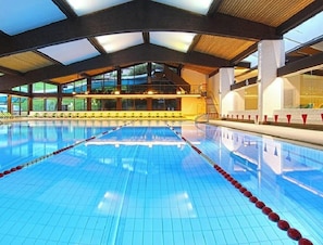 An indoor swimming pool with clear lanes, a high ceiling, and large windows. - "Villa Stella Apartment N 76" near the ski lifts with Wi-Fi and garden (St.Ulrich)