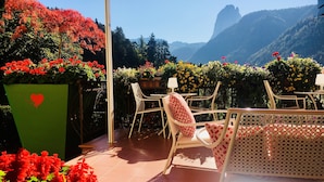 A patio with outdoor furniture, a green planter with a heart symbol, and a view of mountains.