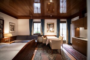 Ein Hotelzimmer mit Holzboden, einer Couch, einem Esstisch, einer Küchenzeile und einem großen Teppich.