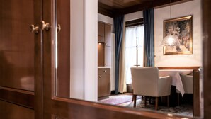 Una habitación con puerta de madera, una zona de comedor con mesa y sillas, un armario y un cuadro en la pared.