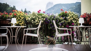Eine Terrasse mit weißen Metallstühlen und -tischen, umgeben von bunten Blumen.