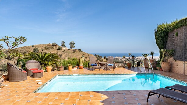 A pool area with lounge chairs, potted plants, and a view of the ocean. - Villa 'Cosy House Jacuzzi Wifi Pool View' with Sea View, Wi-Fi and Air Conditioning (Mijas Pueblo)