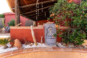 A patio area with a tiled fountain, a cactus, and a potted plant.
