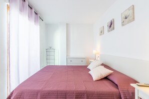 Un dormitorio con una cama grande, una mesita de noche, un armario y una lámpara de pared.