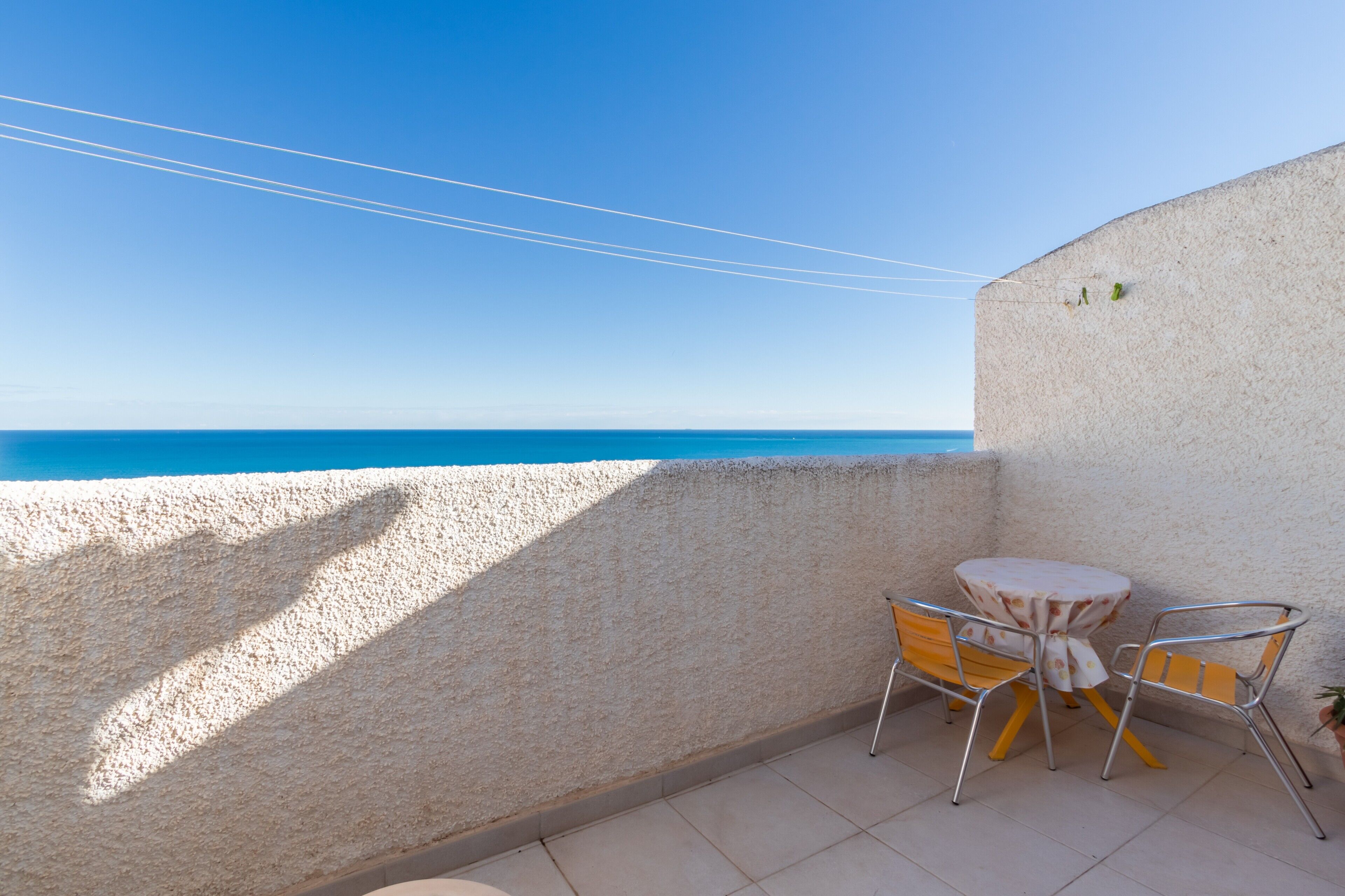 A balcony with a view of the sea, a round table, and two chairs.