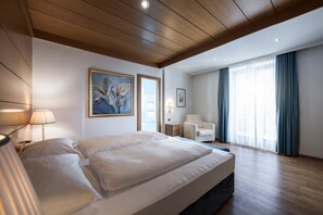 Una habitación de hotel moderna con una cama grande, un escritorio, una silla y un ventanal con cortinas.