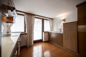 A kitchen with a stove, sink, and cabinets.