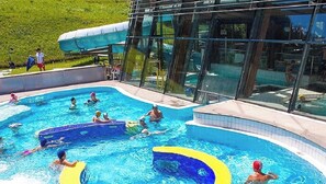 Una piscina con cerramiento de vidrio, rodeada de césped.