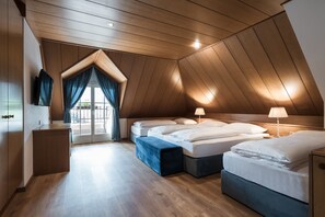 A modern, well-lit attic bedroom with a sloped ceiling, a large window with curtains, and a wooden floor.