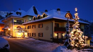 Ein Hotel mit schneebedecktem Dach, einem Weihnachtsbaum und einem Schild mit der Aufschrift 'Villa Stella Residence'.