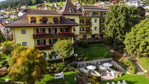 Un hôtel à plusieurs étages doté de balcons, d’un jardin avec des espaces de détente en plein air et offrant une vue sur les collines environnantes.