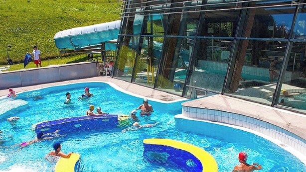 Une piscine dotée d’une enceinte en verre, entourée d’une zone herbeuse.
