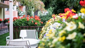 Un jardín con una mesa y sillas blancas, rodeado de flores coloridas y follaje.