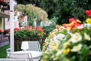 A garden with a white table and chairs, surrounded by colorful flowers and greenery.